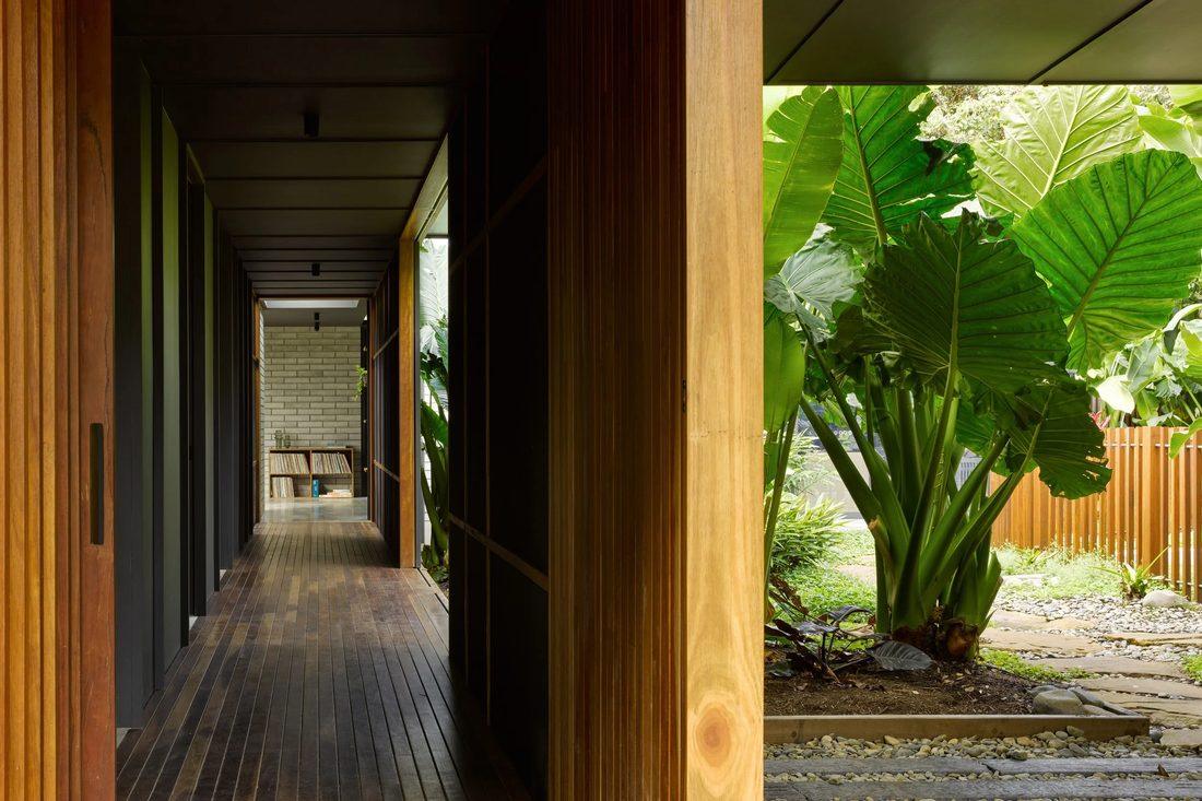 Timber-lined corridor opening to a lush tropical garden